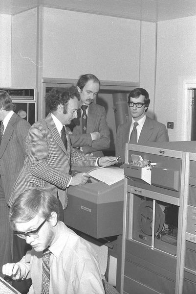 Paul Bryant, Alan Tupman (GEC) and Jim Nisbet (GEC) examining benchmark results; David Duce in the foreground.